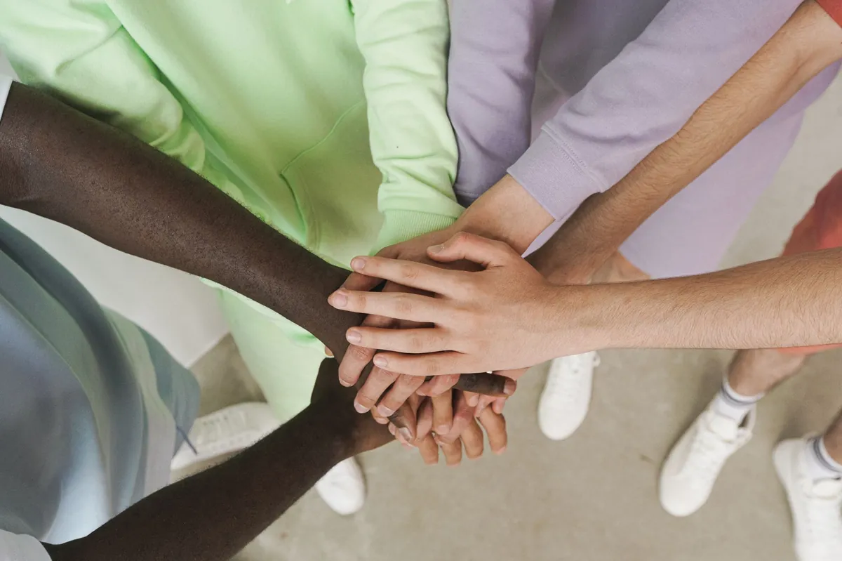 A group of hands stacked together in the center of a circle