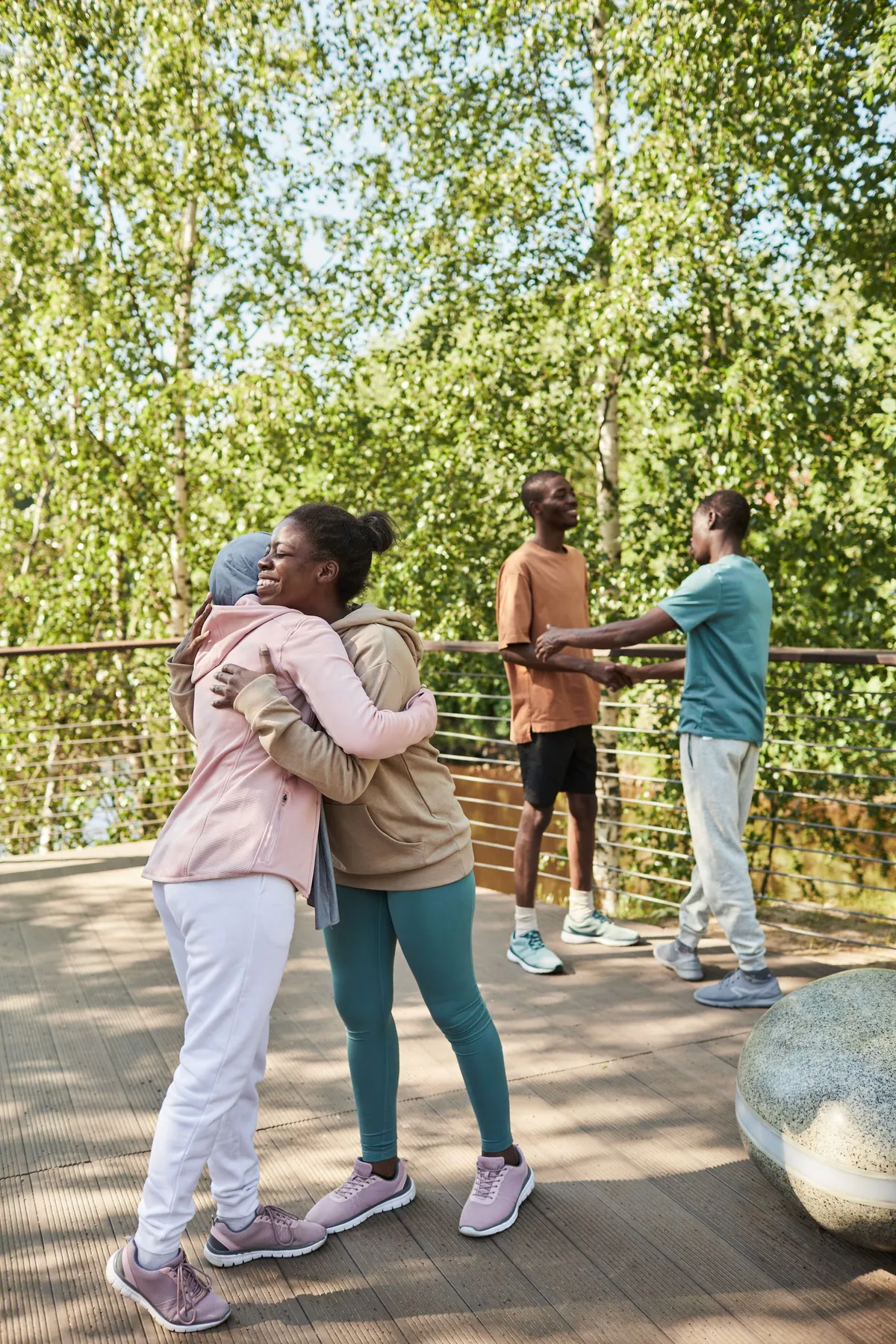 Two people embracing warmly outdoors under summer trees
