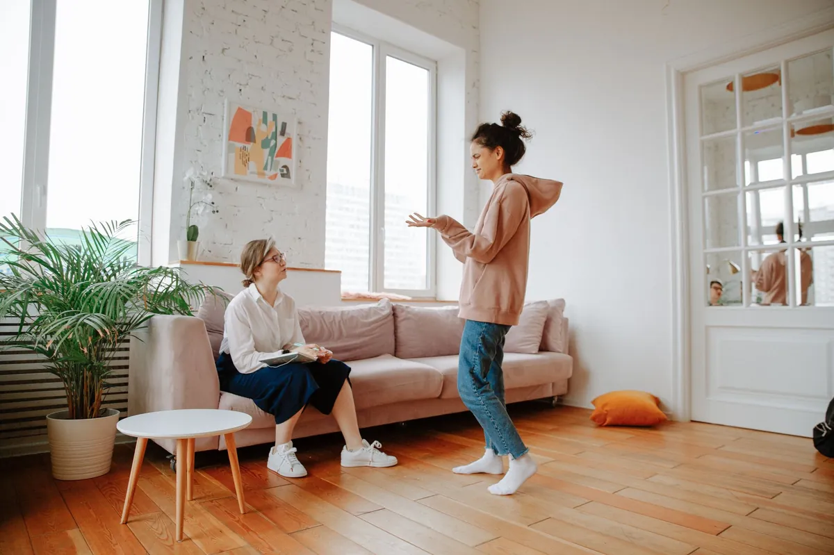 Two women talking comfortably in a bright, welcoming living room