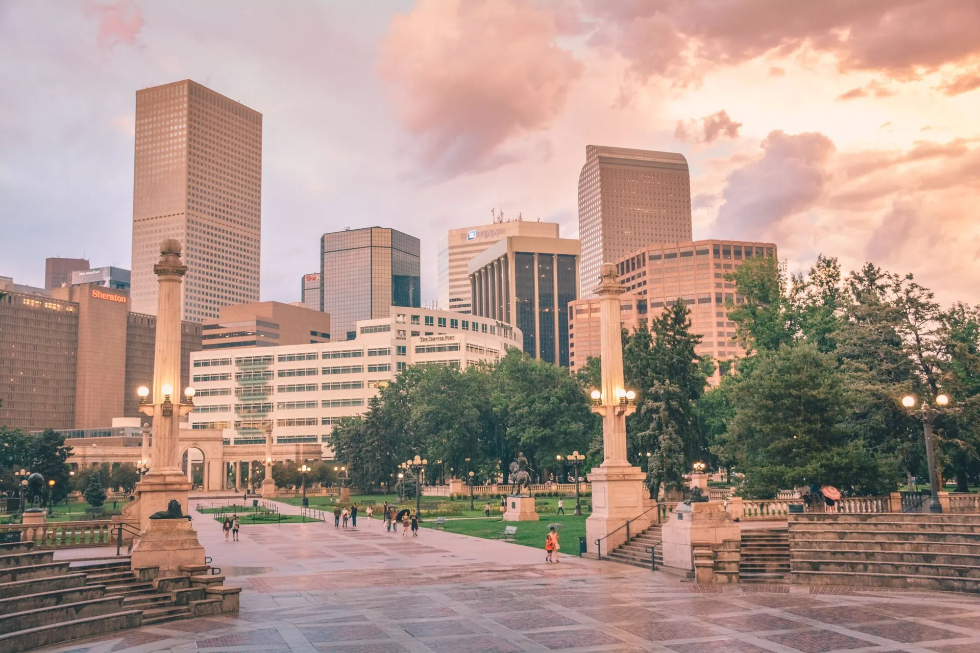 A city park at sunset with people walking through golden light