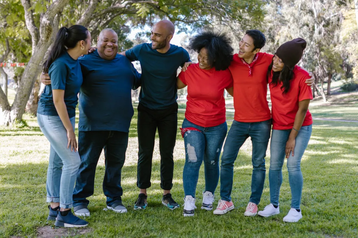 A diverse group of friends standing arm in arm in a sunny park