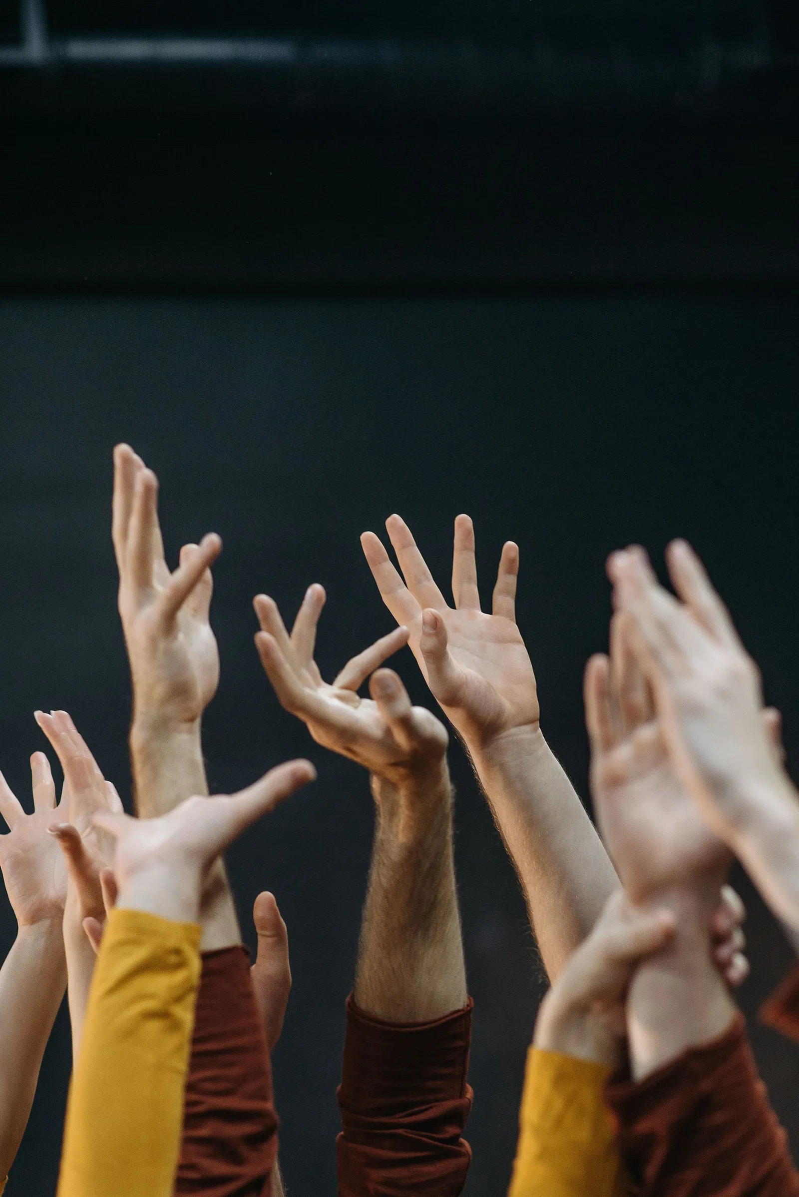 Open hands raised together against a dark background