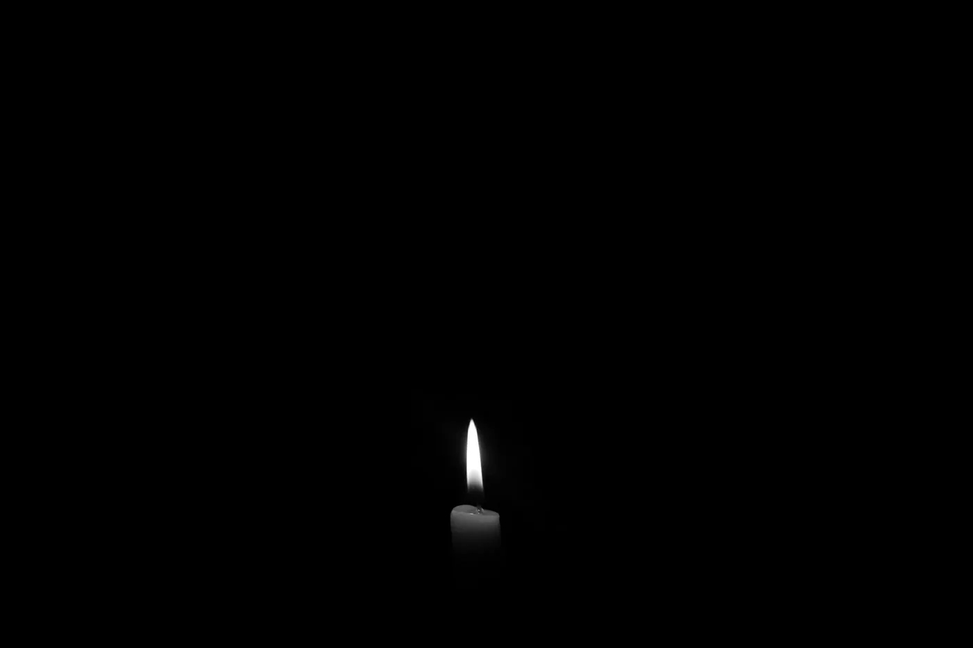 A single small candle flame burning in complete darkness