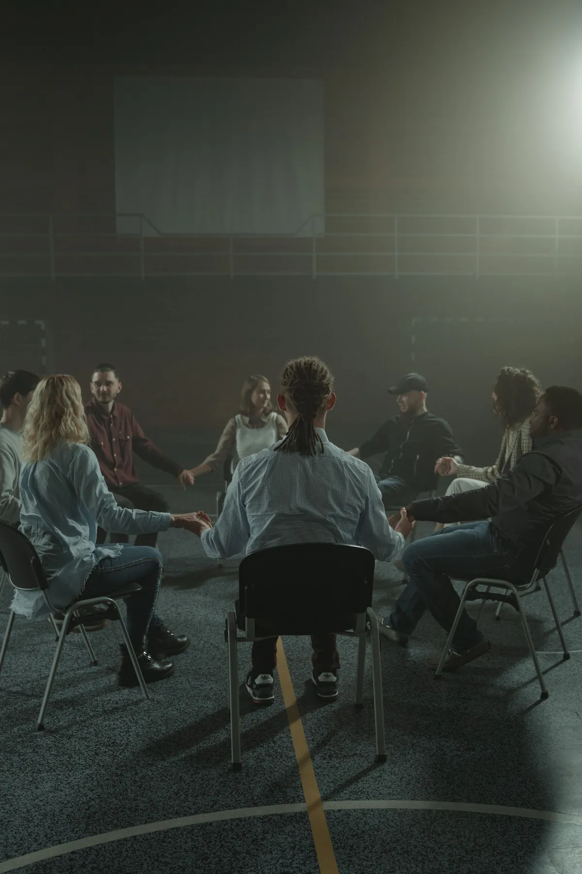 A dimly lit circle of people seated close together in conversation