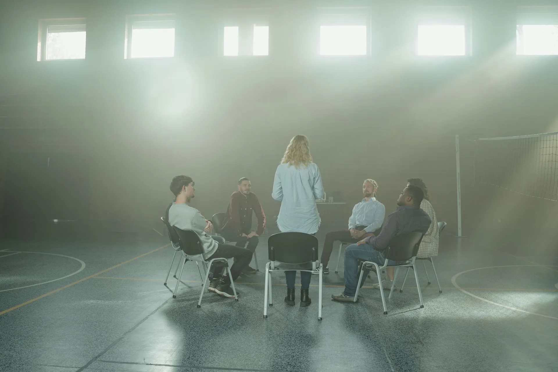 A support circle gathered on chairs in a hall filled with soft window light
