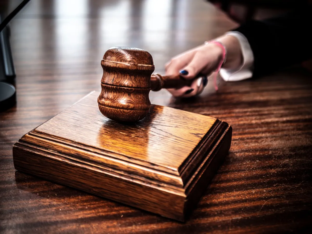 A wooden gavel resting on a judge's desk in warm light