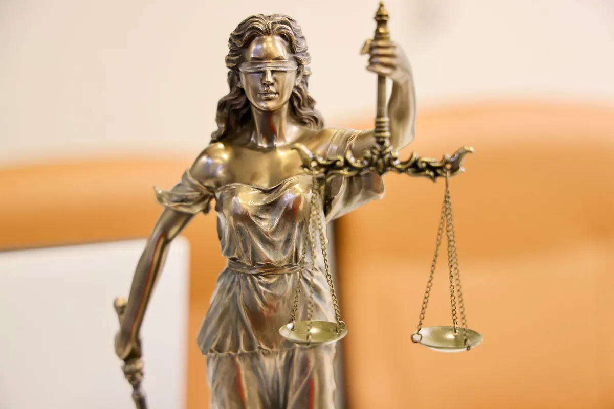 A statue of Lady Justice holding balanced scales in warm light