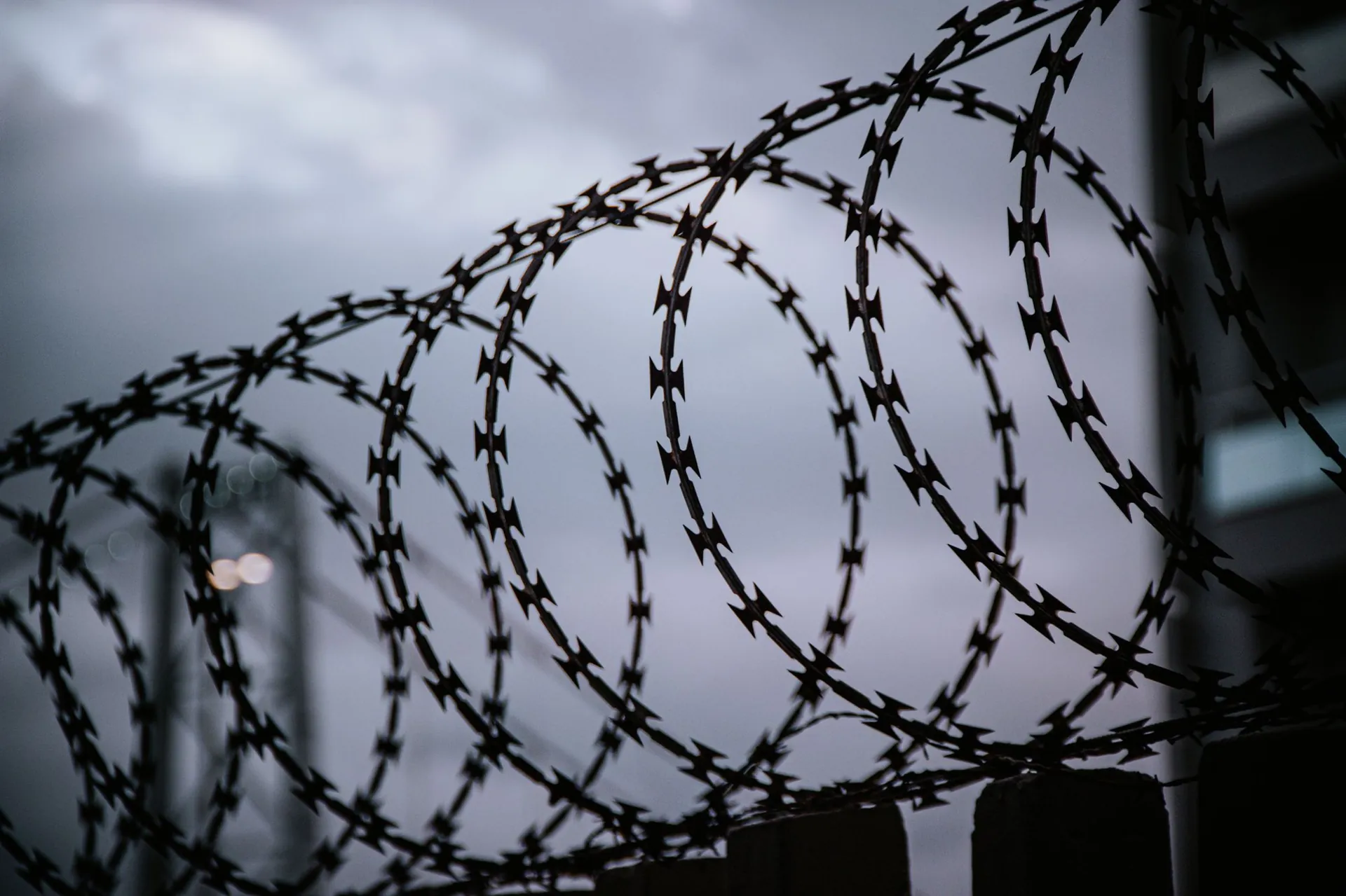 Coils of razor wire silhouetted against a heavy grey sky