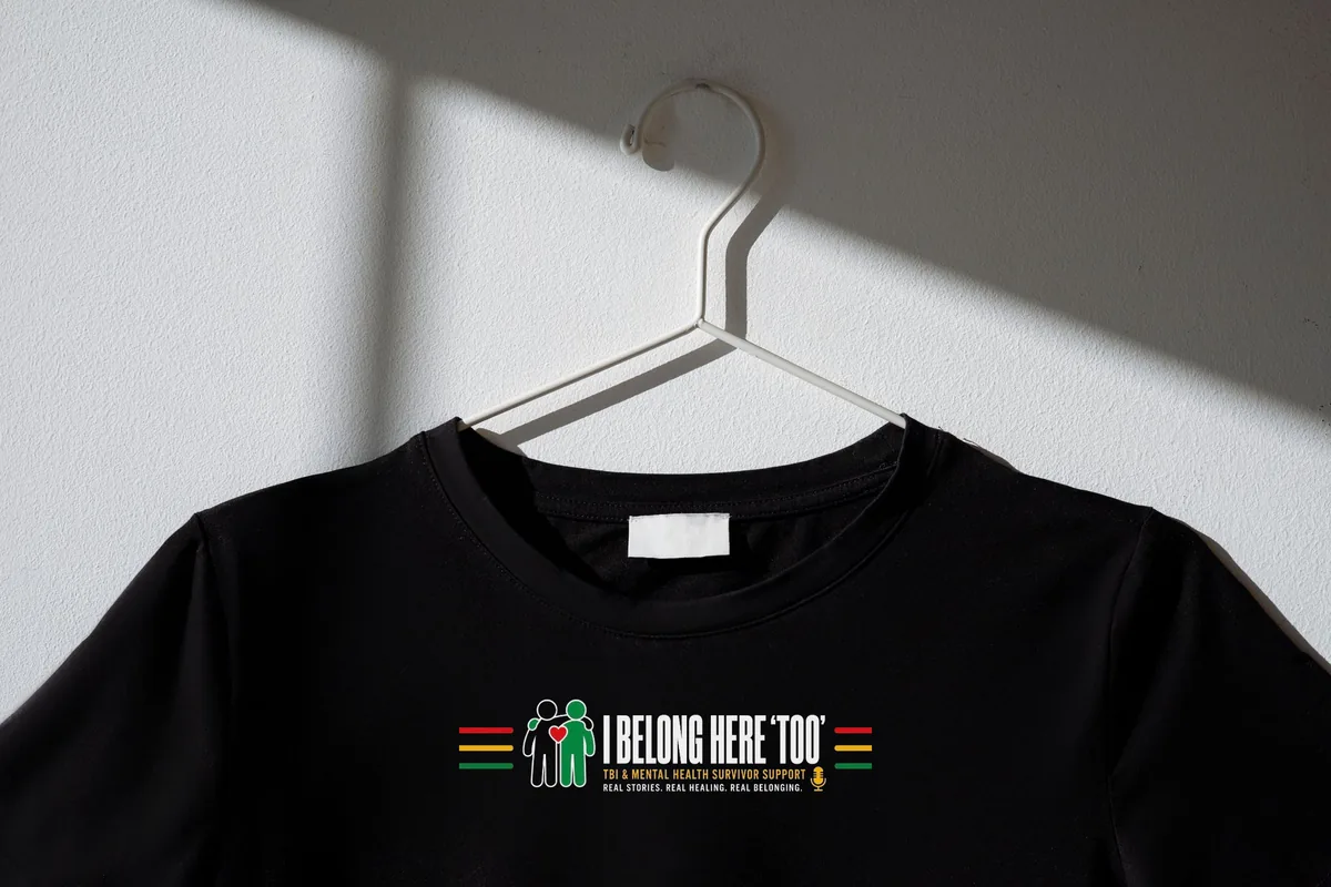 Black t-shirt on a hanger with the full I Belong Here TOO chest print