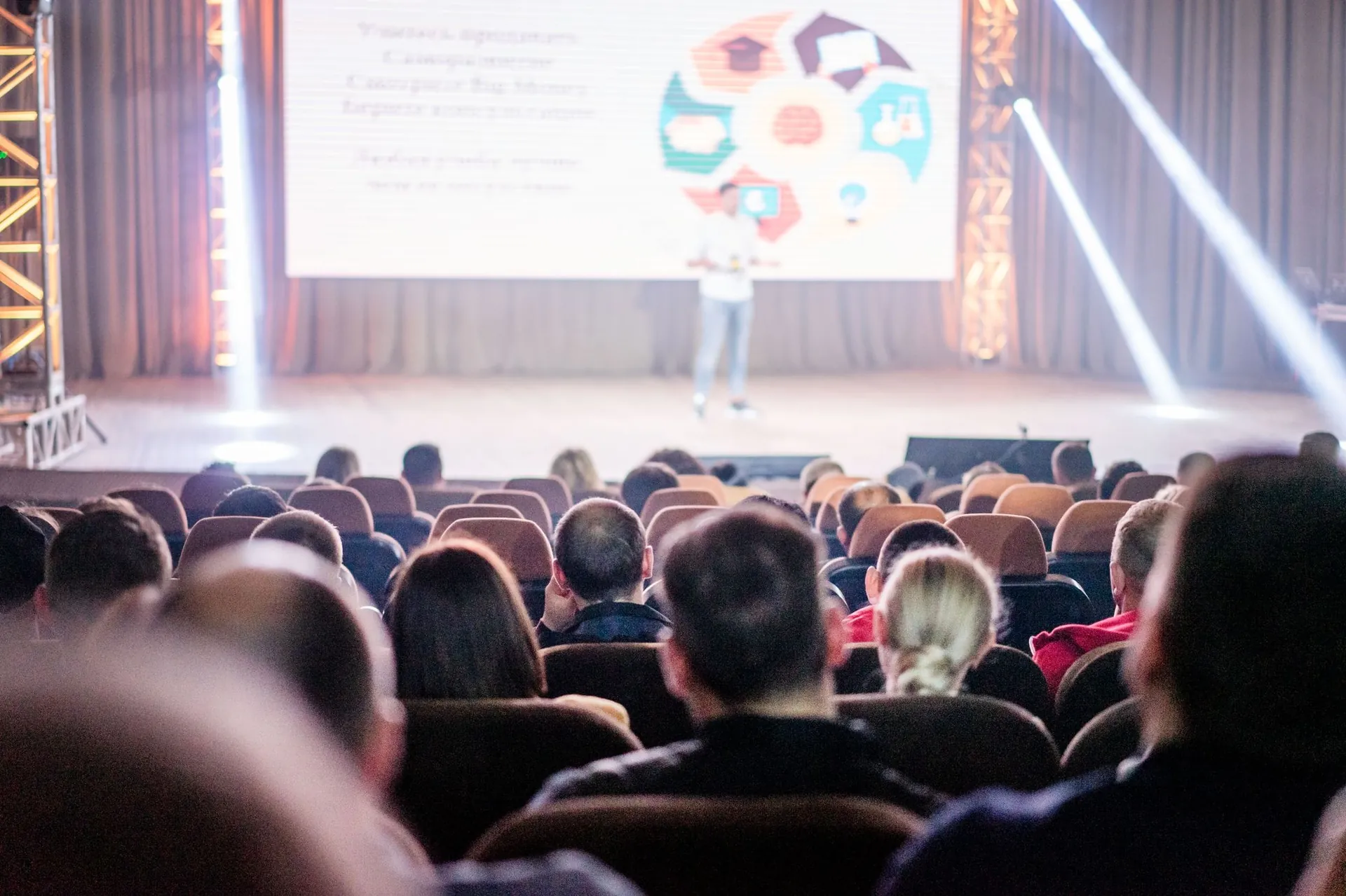 An audience watching a presentation under bright stage lights