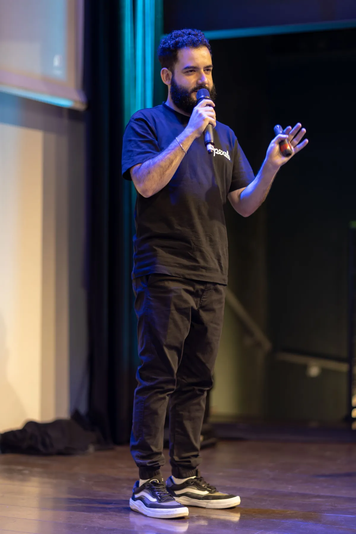 A speaker holding a microphone while addressing an audience from stage