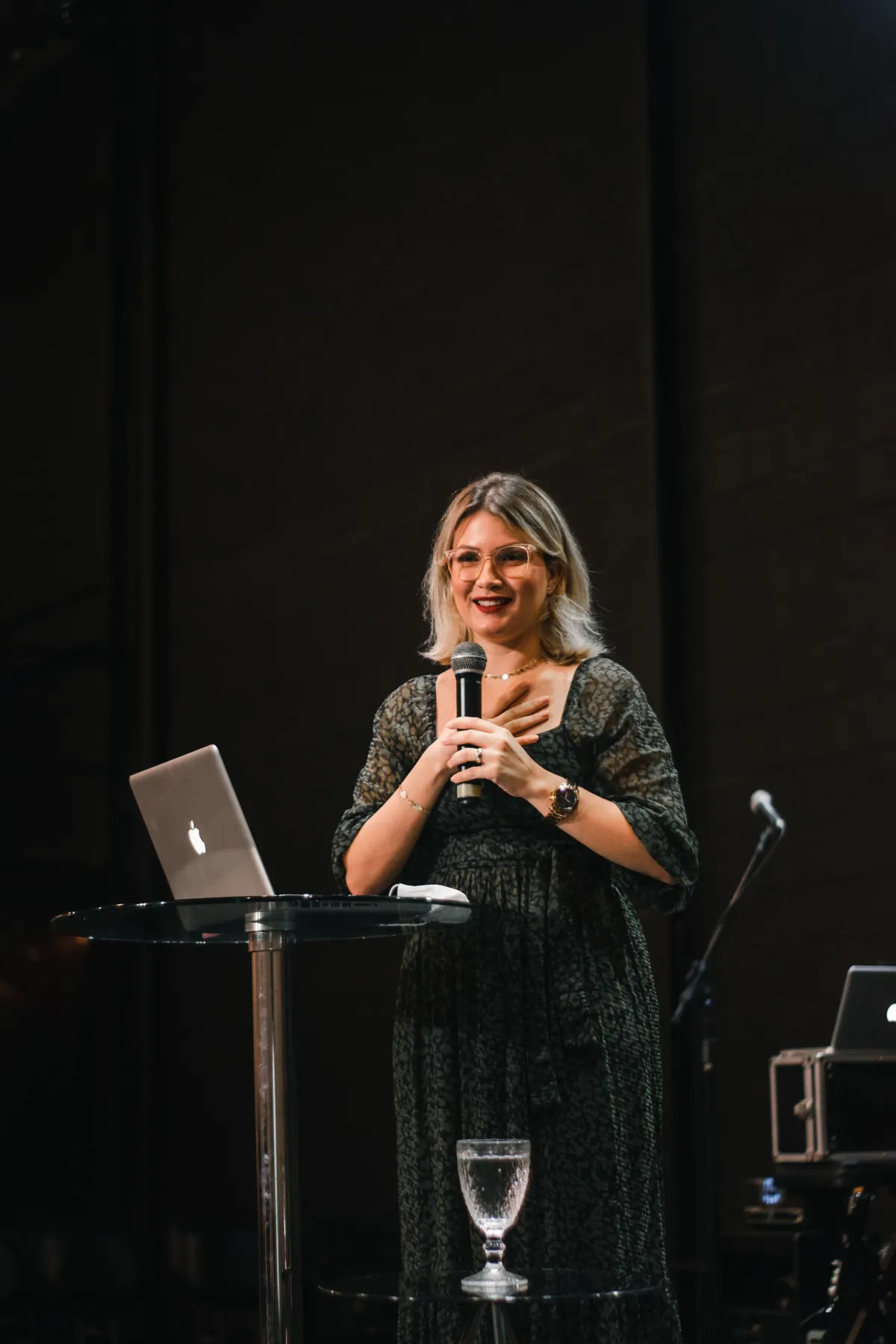 A woman speaking at a lectern with a laptop and microphone