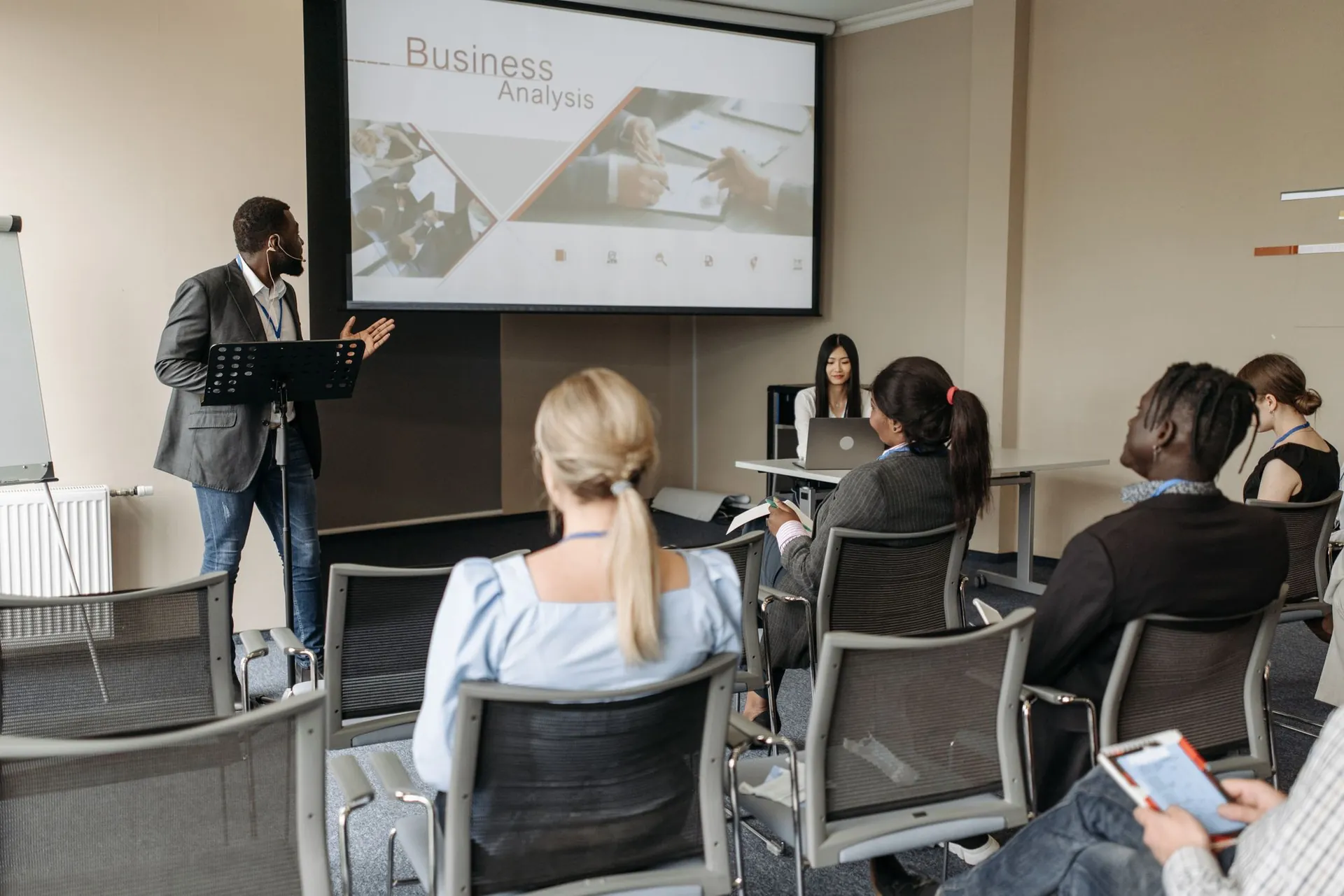 A trainer presenting to professionals in a modern seminar room